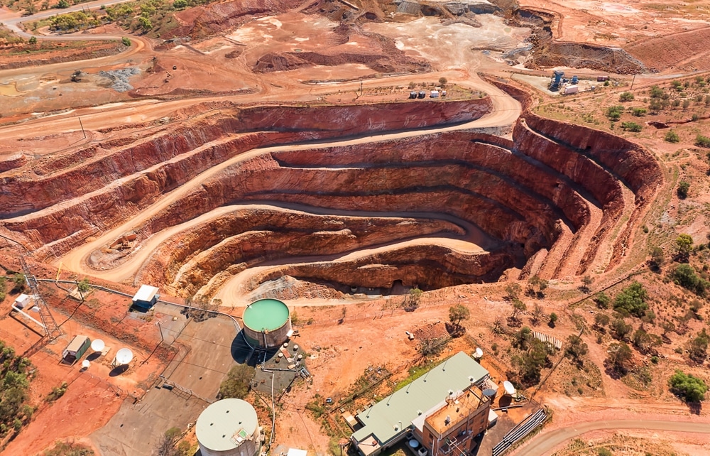 Red Australian OUtback soil in Cobar town with open pit copper mine - aerial top down view.